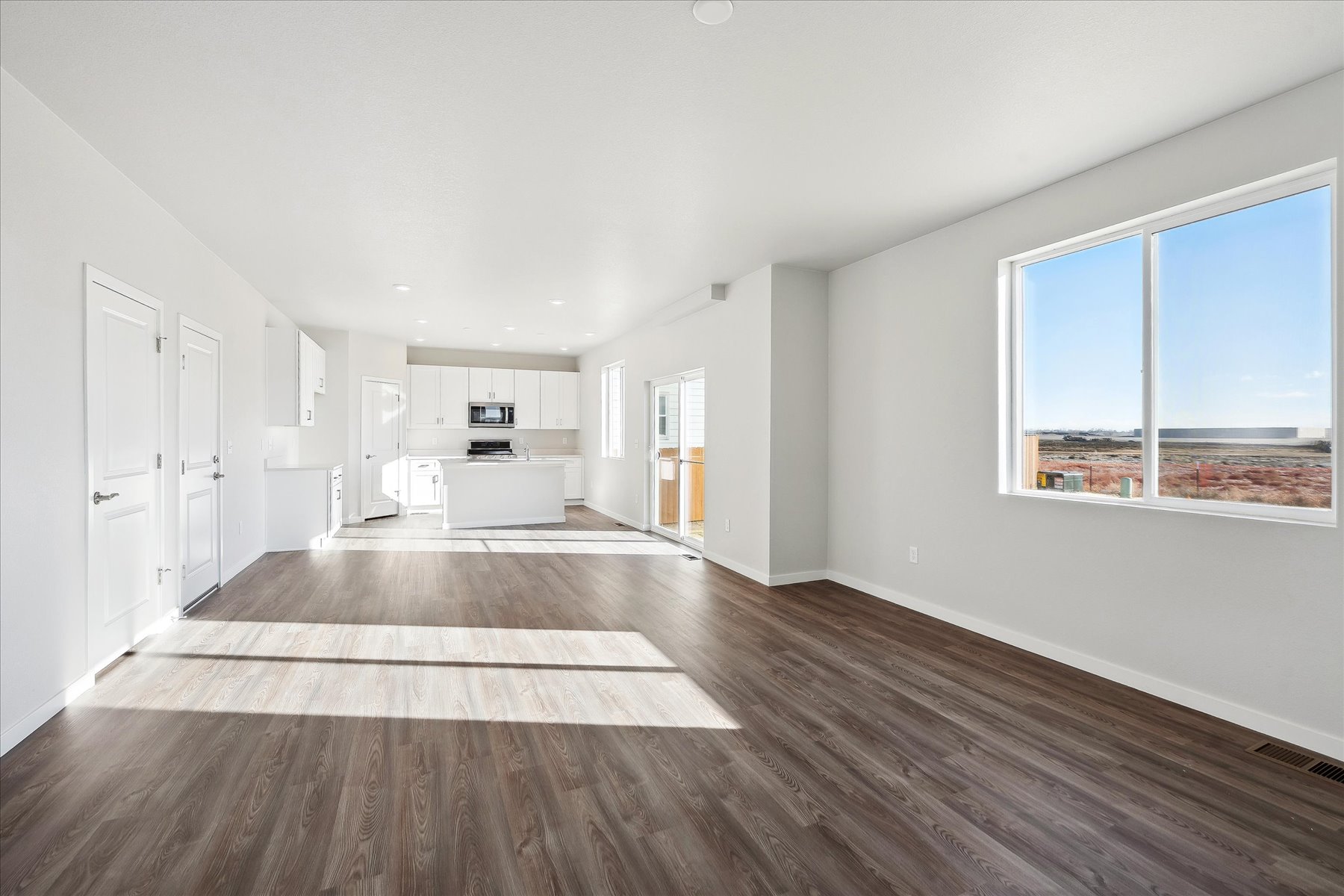 A large empty room with a wood floor and a large window.