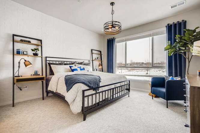 A bedroom with a bed and a chair.