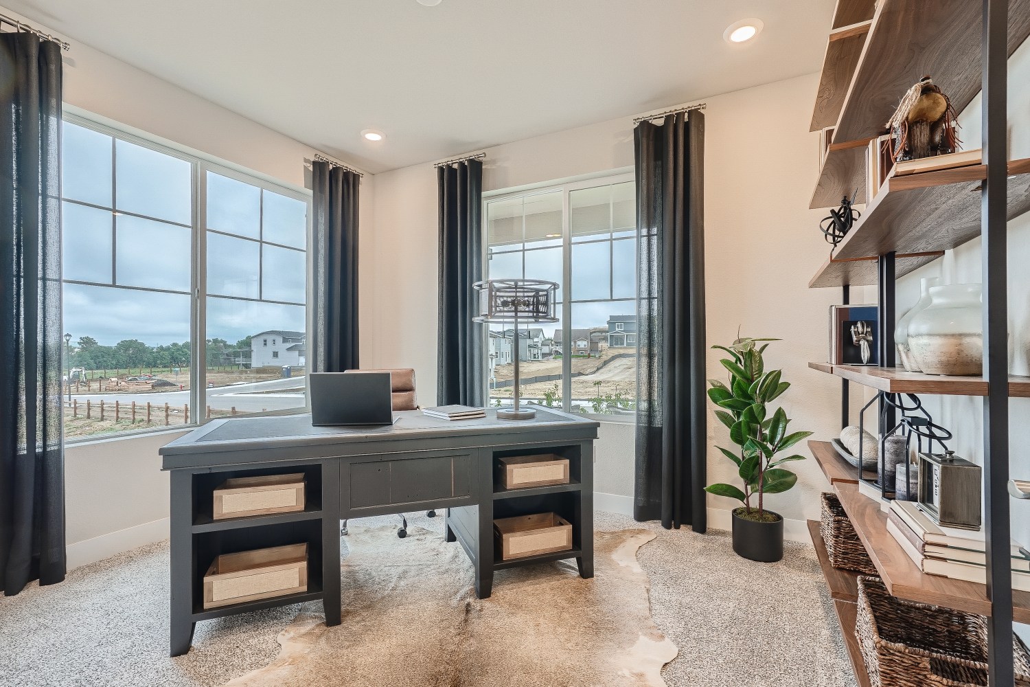 A room with a desk and a window with a view of a city.