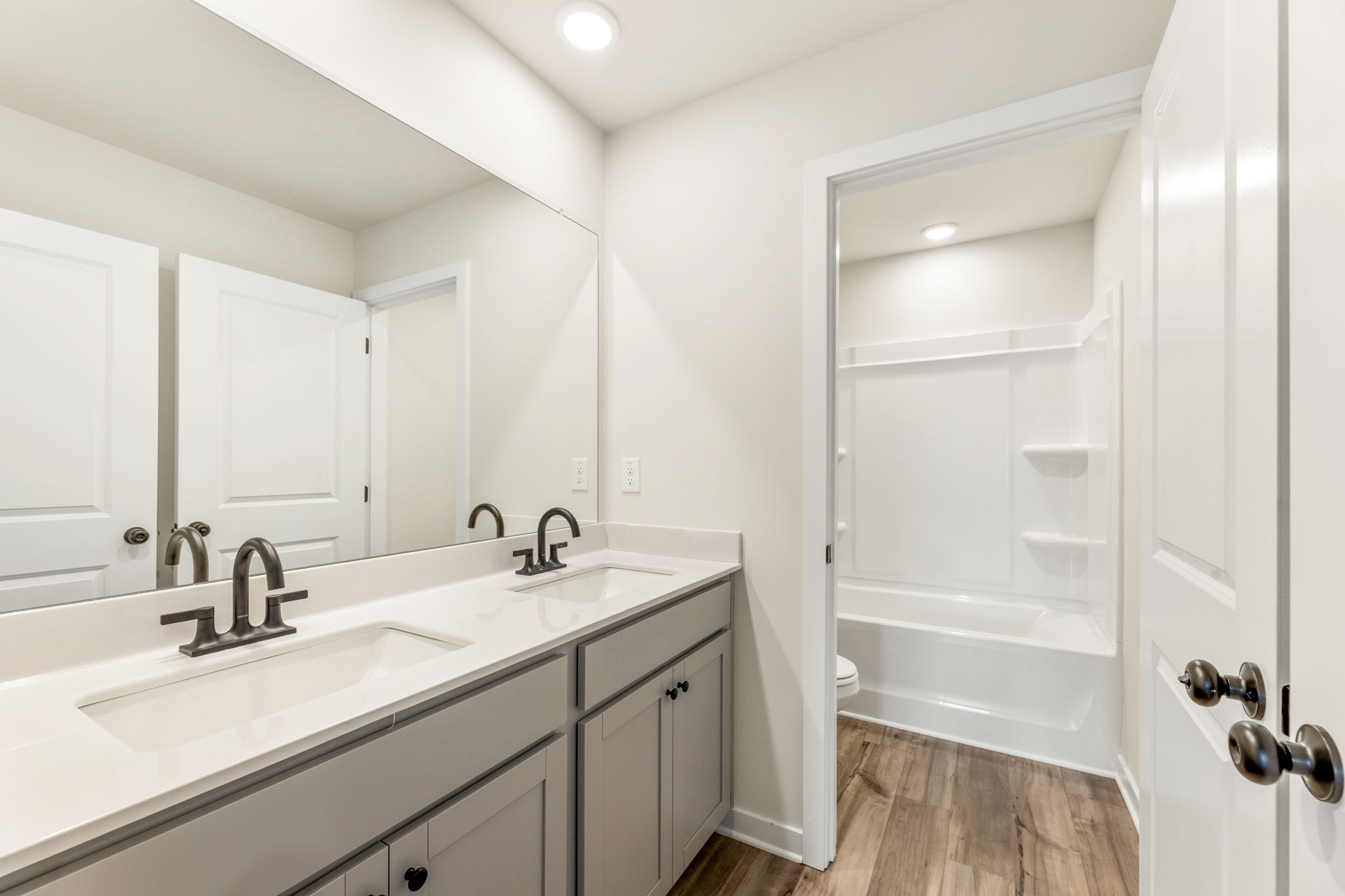 A bathroom with a tub sink and a mirror.