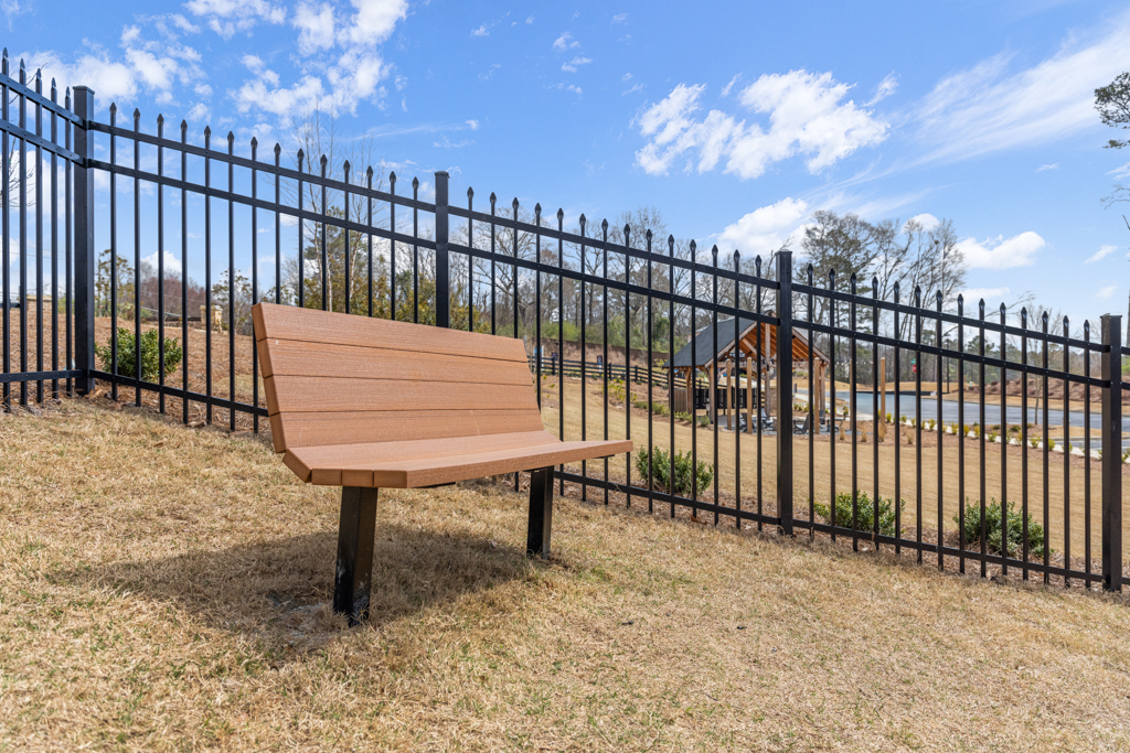A wooden bench in front of a fence.