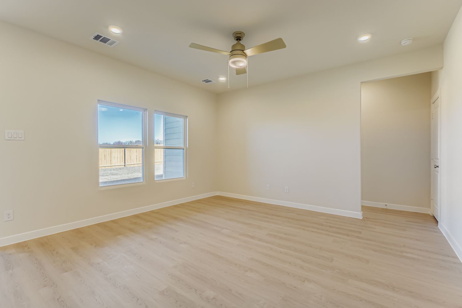 A room with a wood floor and a ceiling fan.