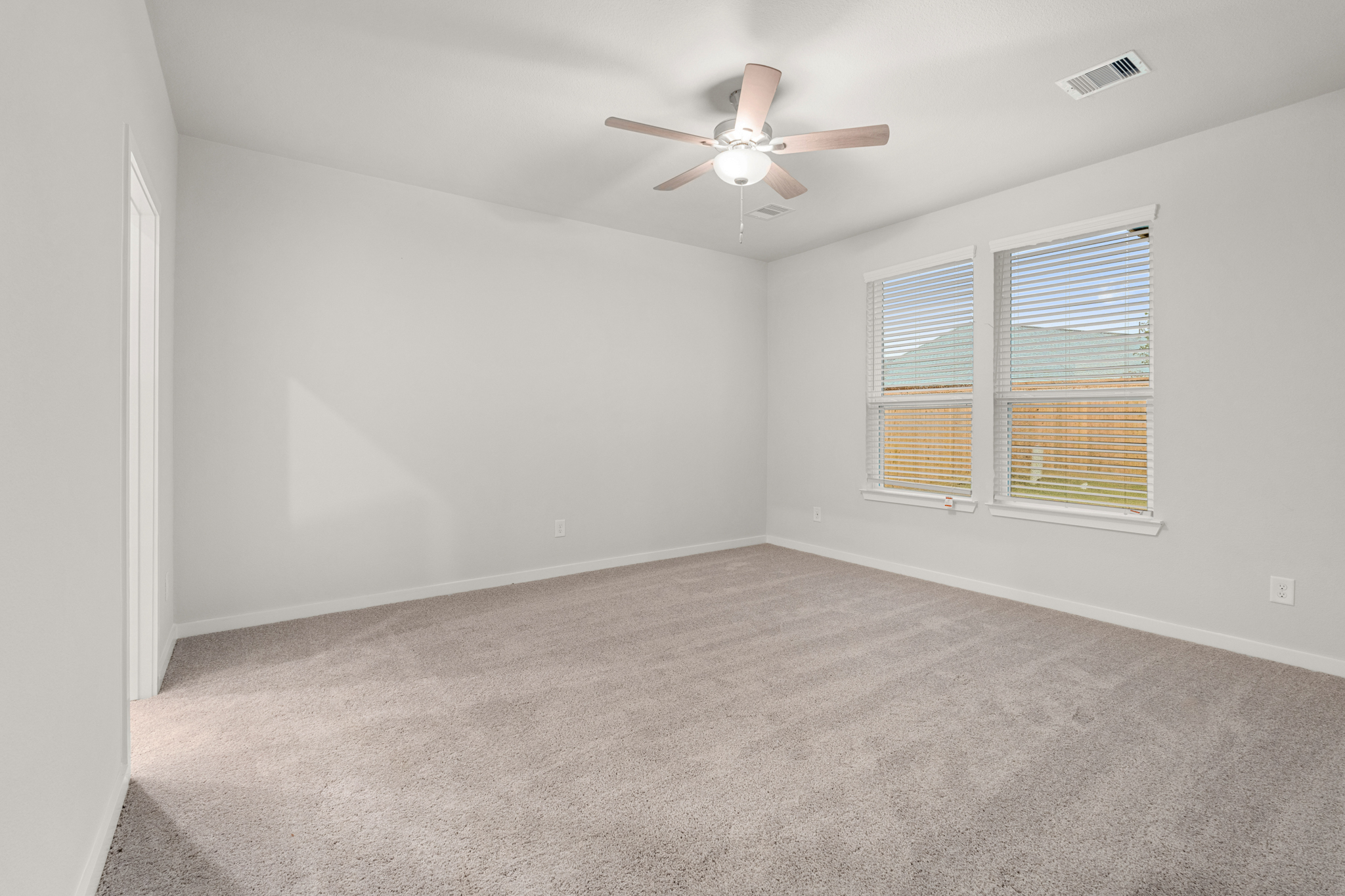 A room with a ceiling fan and a carpet.
