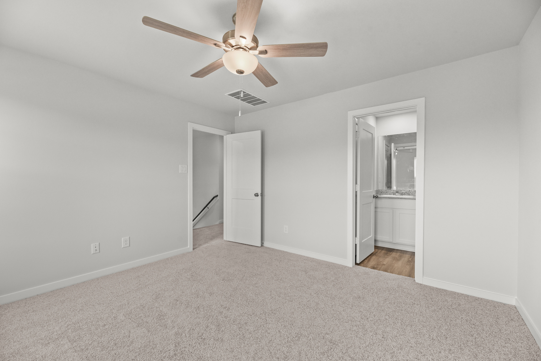 A room with a ceiling fan and a door.