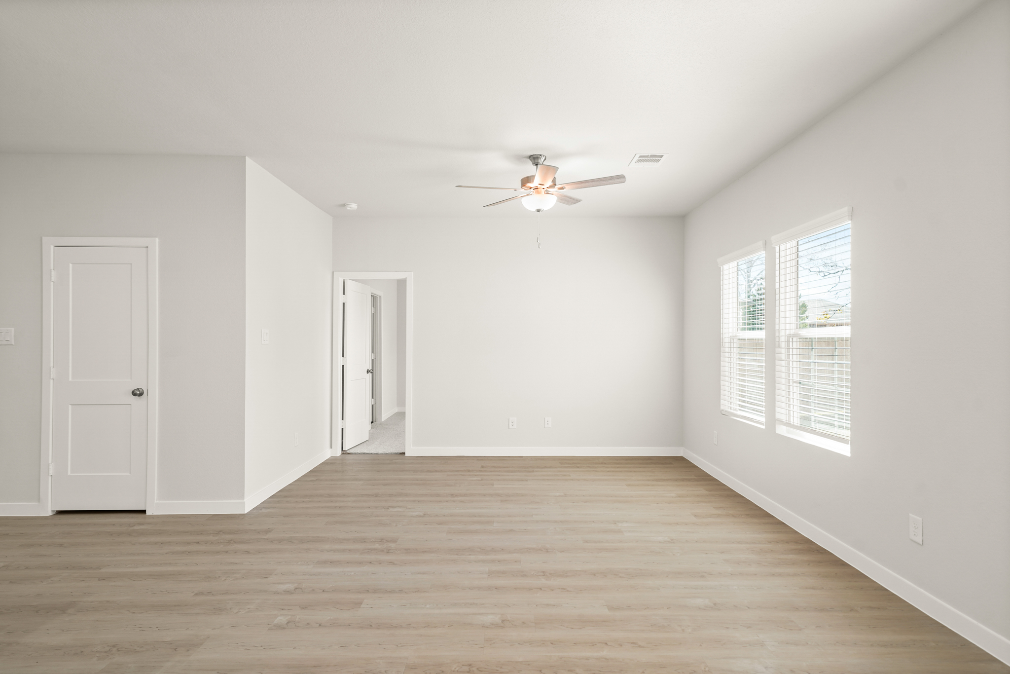 A room with a wood floor and a ceiling fan.