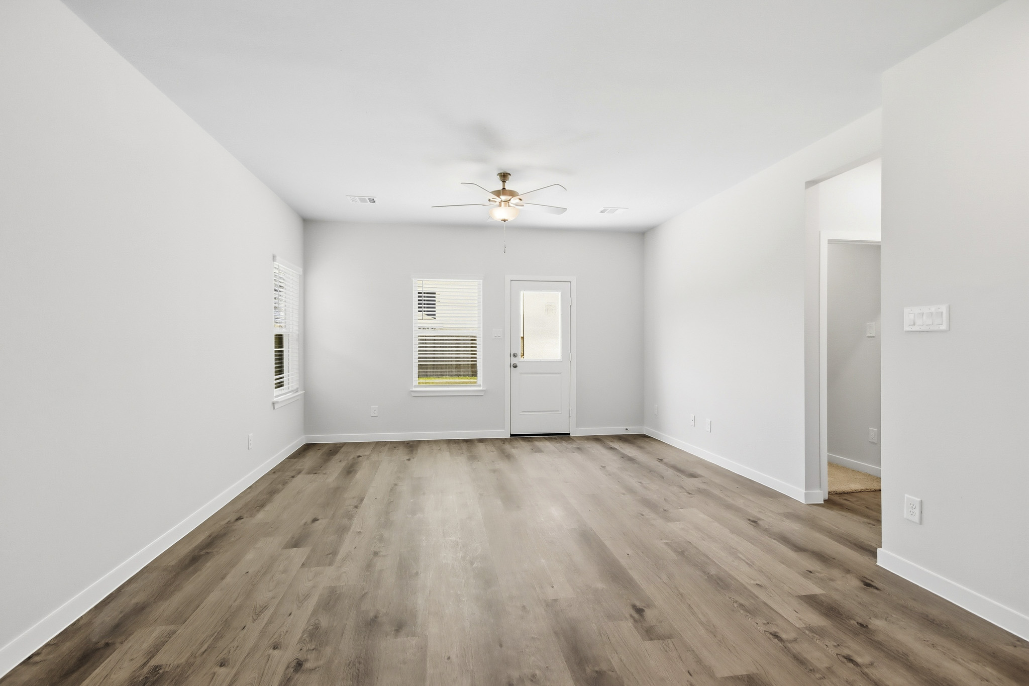 A room with a wood floor and a ceiling fan.