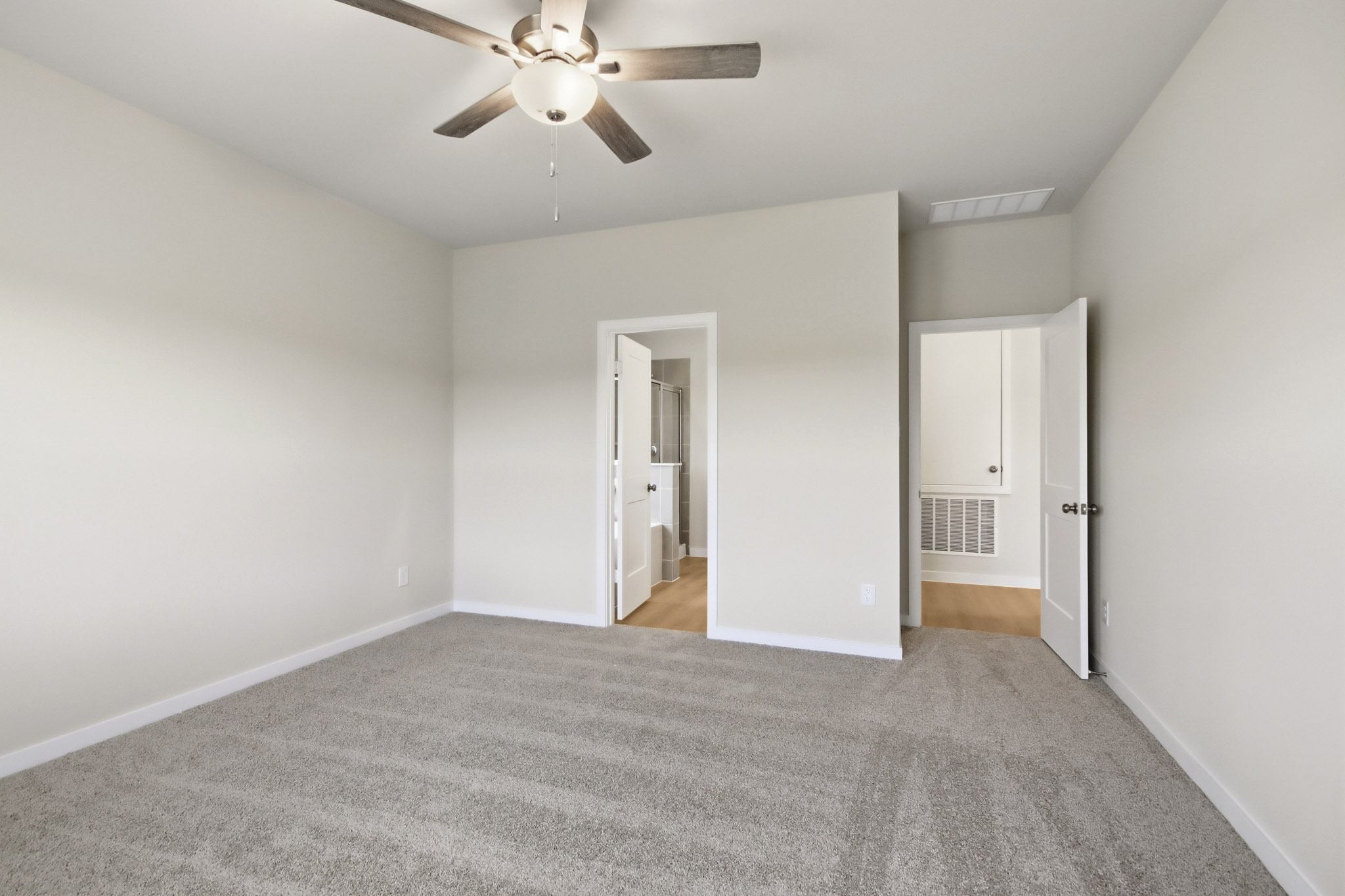 A room with a ceiling fan and a carpet.