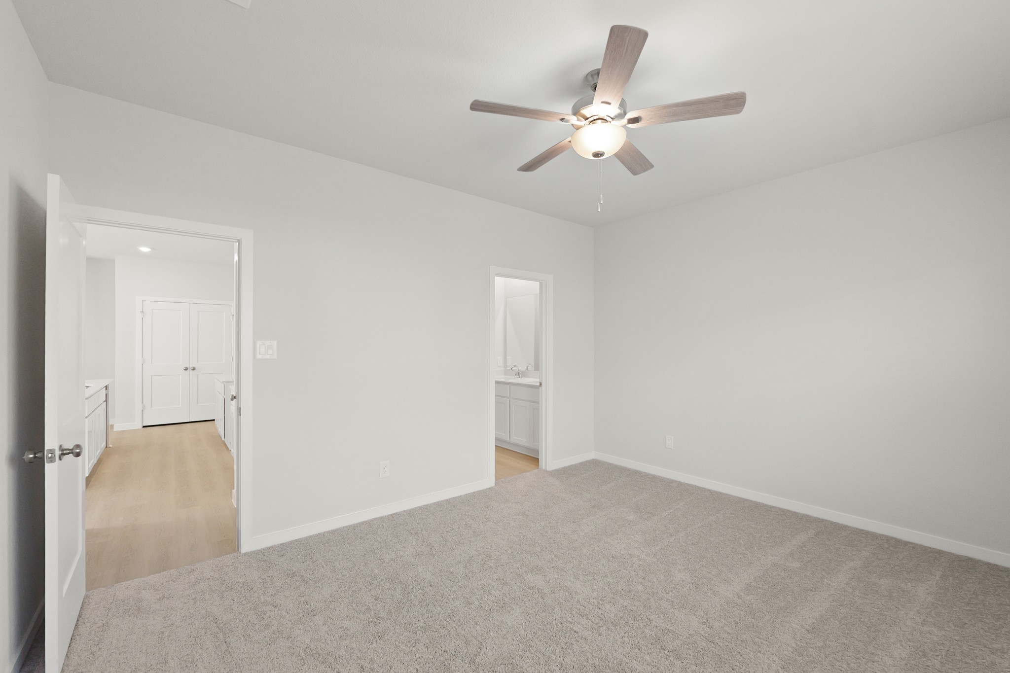 A room with a ceiling fan and a door.