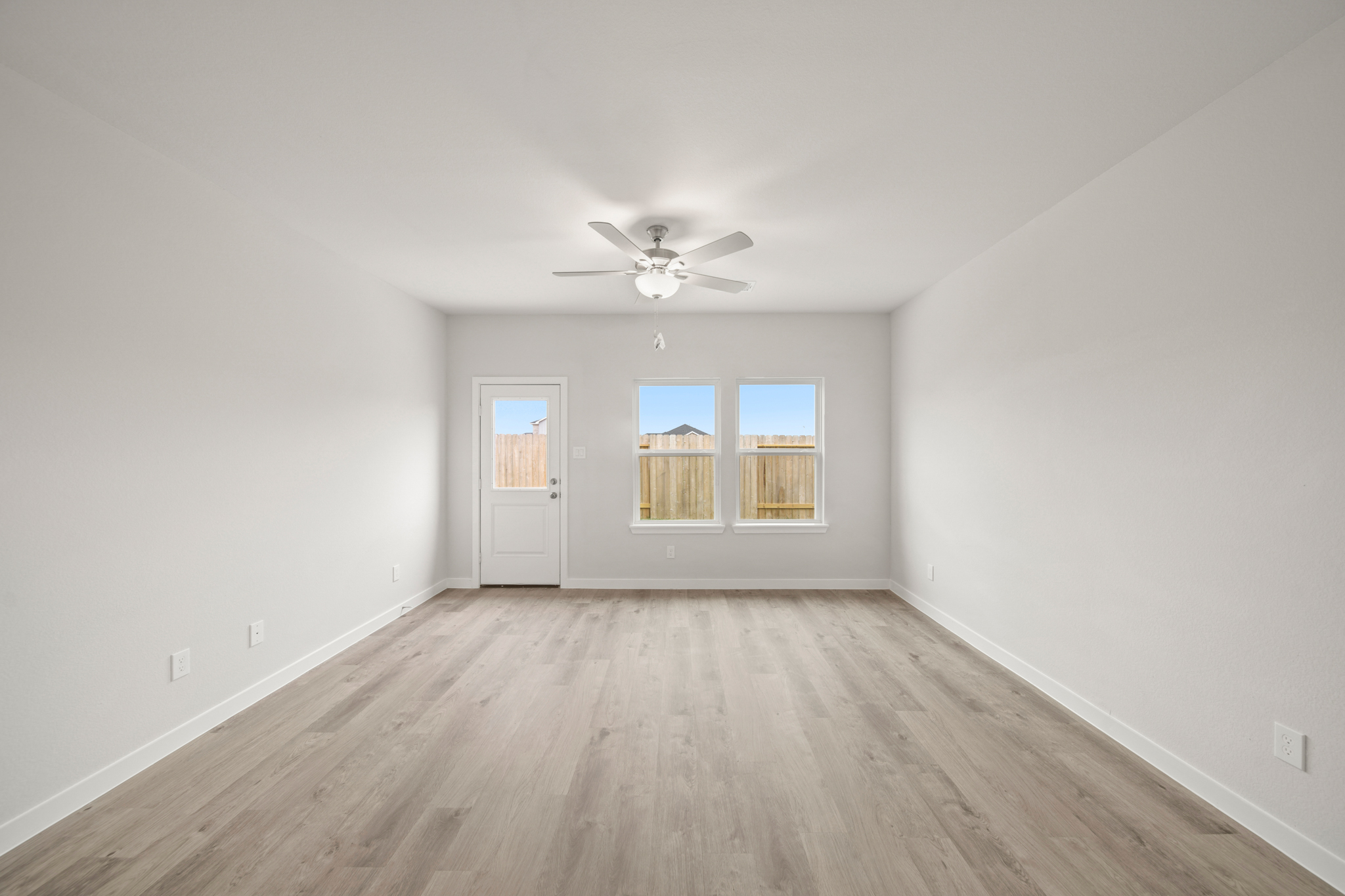 A room with a ceiling fan and a wood floor.