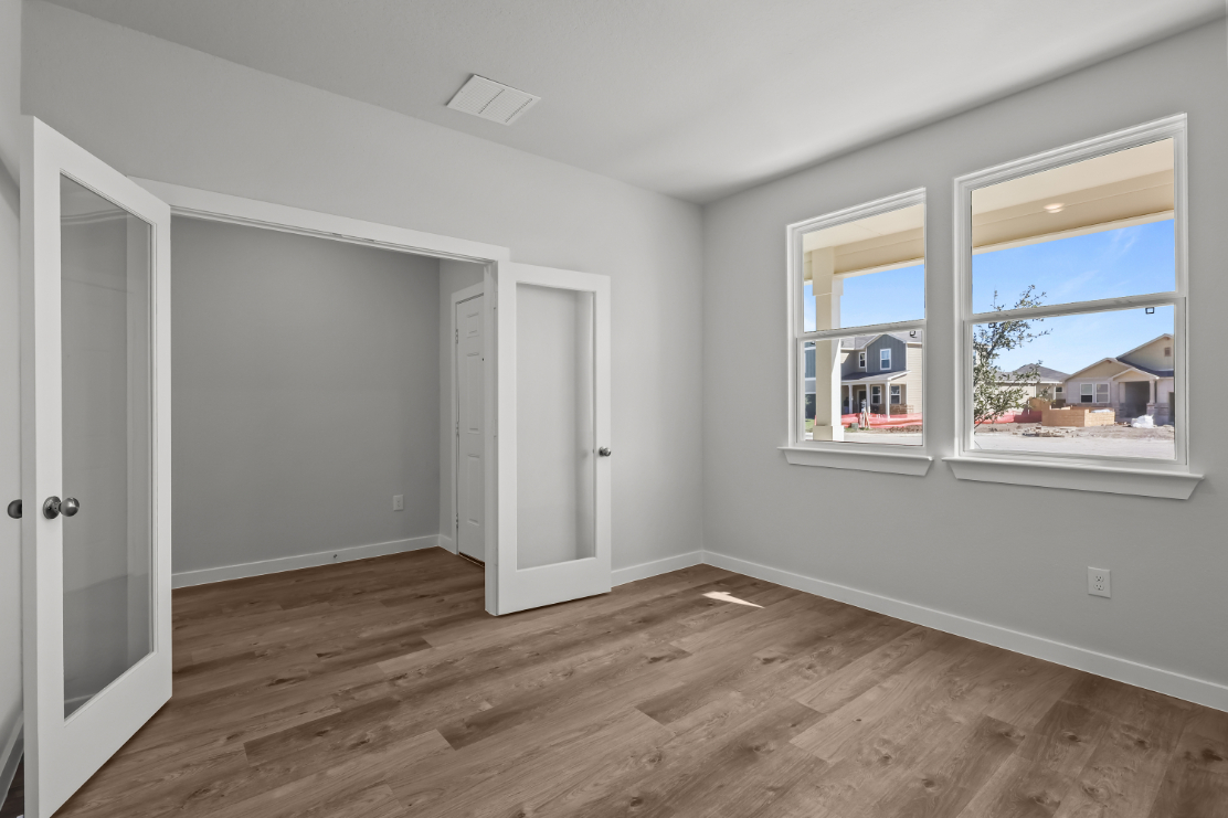 A room with a wood floor and a window with a view of the ocean.