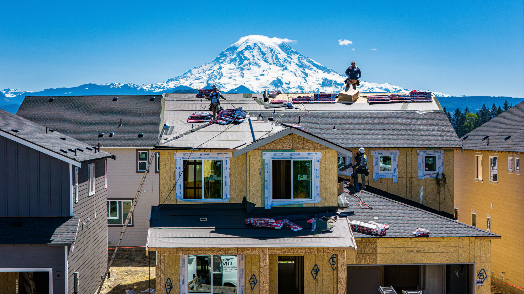 A group of men on top of a building with a mountain in the background.