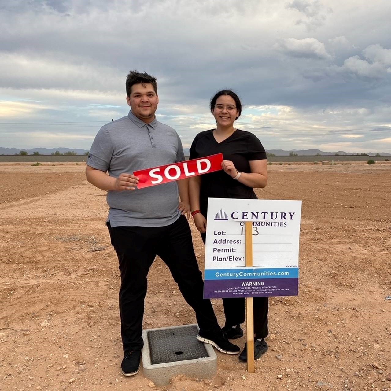 A man and woman posing for a picture with a sign.